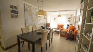 Un comedor con una mesa y sillas de madera oscura, un mapa mundial en la pared y una estantería con libros.