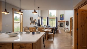 Une cuisine spacieuse avec des meubles en bois, un grand îlot central, un éclairage suspendu et une vue sur l’extérieur.