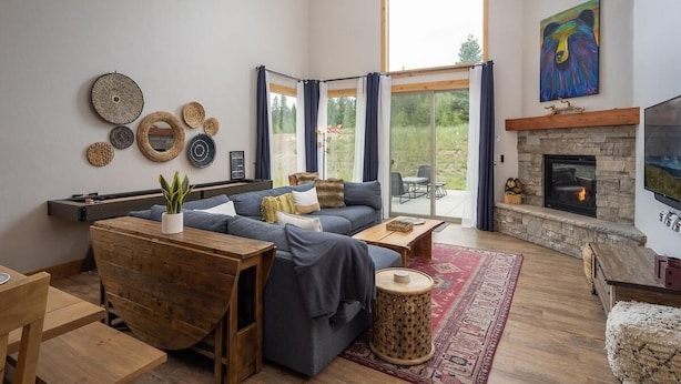 Un salon moderne avec une cheminée en pierre, une grande fenêtre et un coin salon confortable.