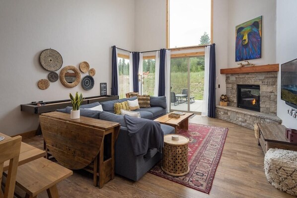 A modern living room with a stone fireplace, a large window, and a cozy seating area.