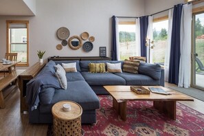 A modern living room with a sectional sofa, a wooden coffee table, and a patterned rug.