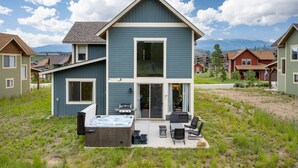 Une maison à deux étages dotée d’un patio comprenant un espace salon extérieur et un jacuzzi.