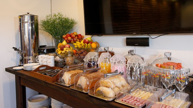 Un buffet proposant une variété d’aliments et de boissons, notamment des fruits, du pain et de la viande.