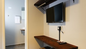 Un couloir avec un banc en bois, un téléviseur fixé au mur et une porte donnant sur une autre pièce.