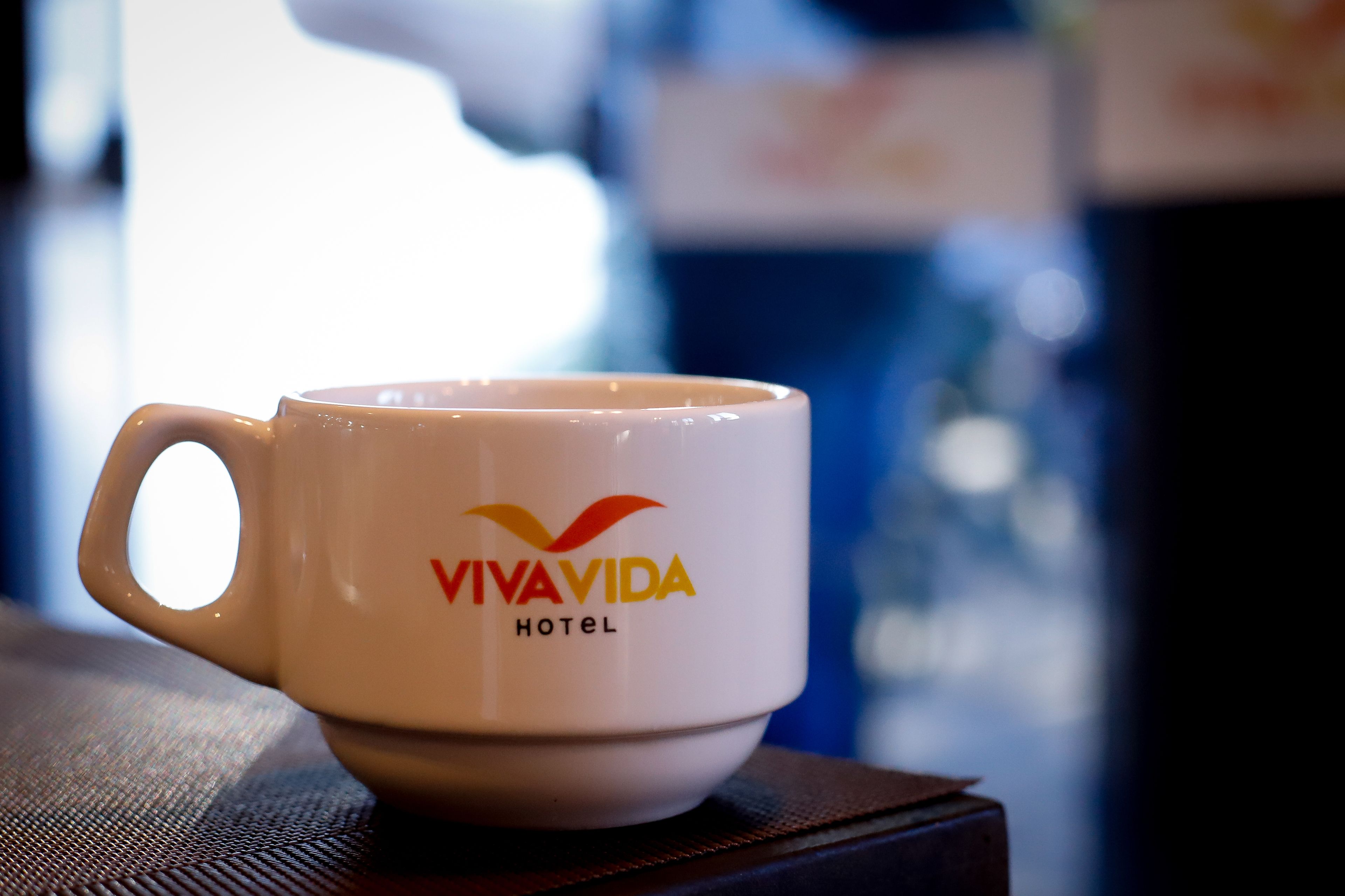A white mug with the text "VIVAVIDA HOTEL" on it.