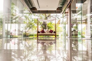 Relax in a serene space with a canopy bed and expansive views of lush trees and the sky.