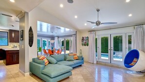 Un salón espacioso con un sofá modular, un comedor y vista a una piscina.