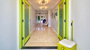Un pasillo con puertas de marco verde, un banco y una lámpara en el techo.