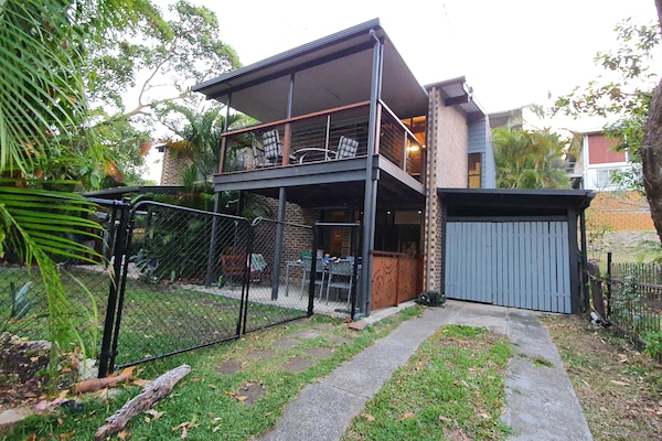 Front of house showing secure fence, yard, garage and top deck.