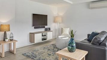 A modern living room with a flat-screen TV, a sofa, a coffee table, and a lamp.