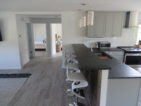 A modern kitchen with a bar area, grey cabinets, and a microwave.