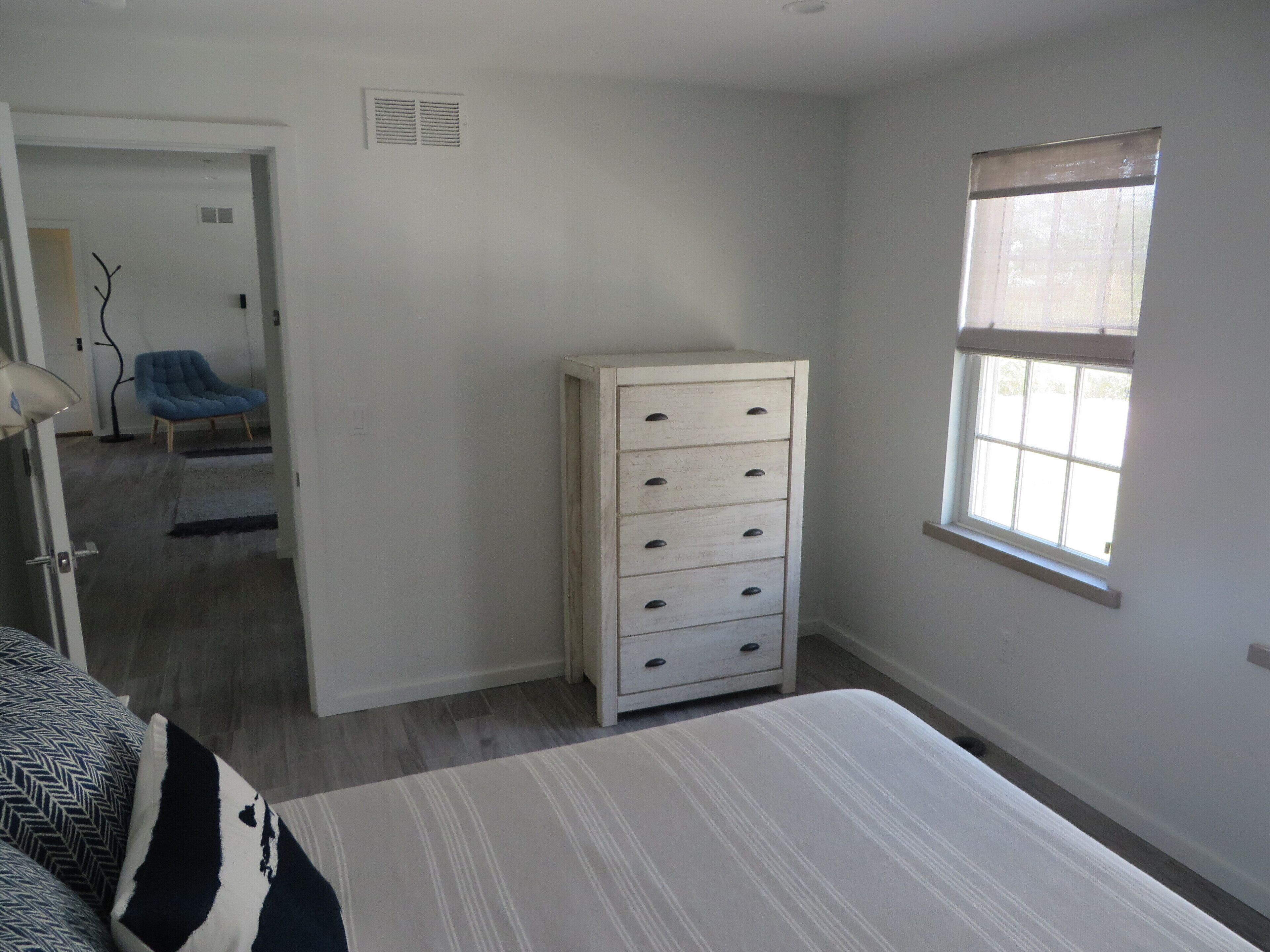 A bedroom with a bed, a dresser, a chair, and a window.