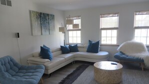 Ein modernes Wohnzimmer mit einem weißen Modulsessel, einem blauen Sessel und einem runden Couchtisch.