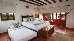 A bedroom with two beds, a hammock, and a view of the outdoors. - Casa de las flores (Villa de Leyva)