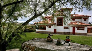 A traditional building with a tiled roof, white walls, and red accents. - Casa de las flores (Villa de Leyva)