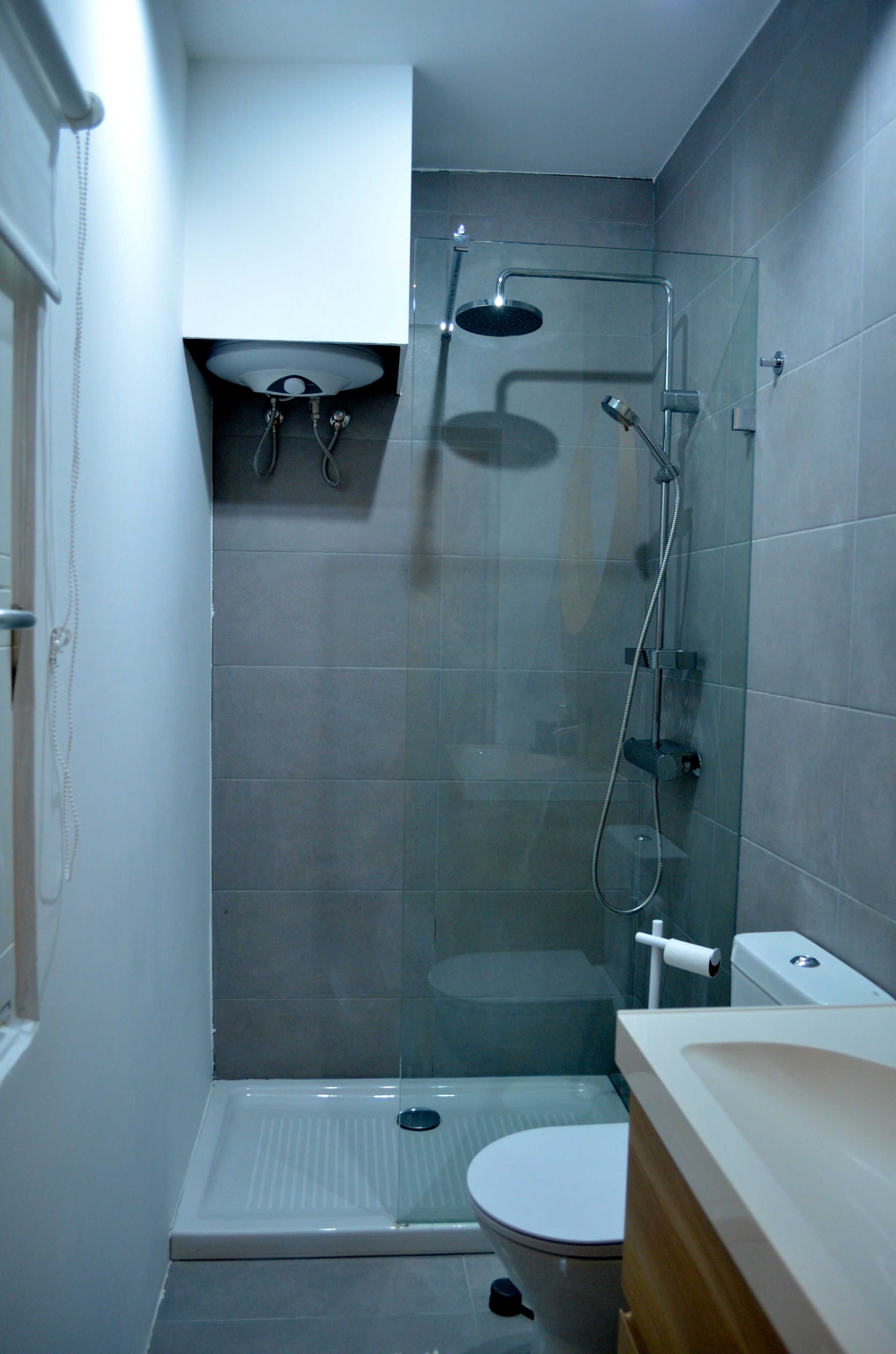 A compact bathroom with a glass-enclosed shower, a white toilet, and a sink with a wooden countertop.