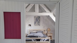 Ein Schlafzimmer mit einem Bett, einem Nachttisch, einer Lampe und einer roten Tür.