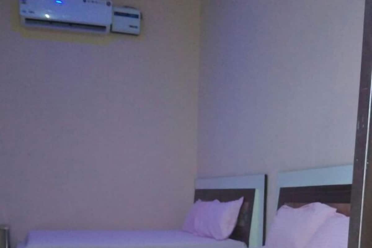 Habitación individual con una cama y cabecera de madera, un televisor de pantalla plana en la pared y suelo de baldosas.