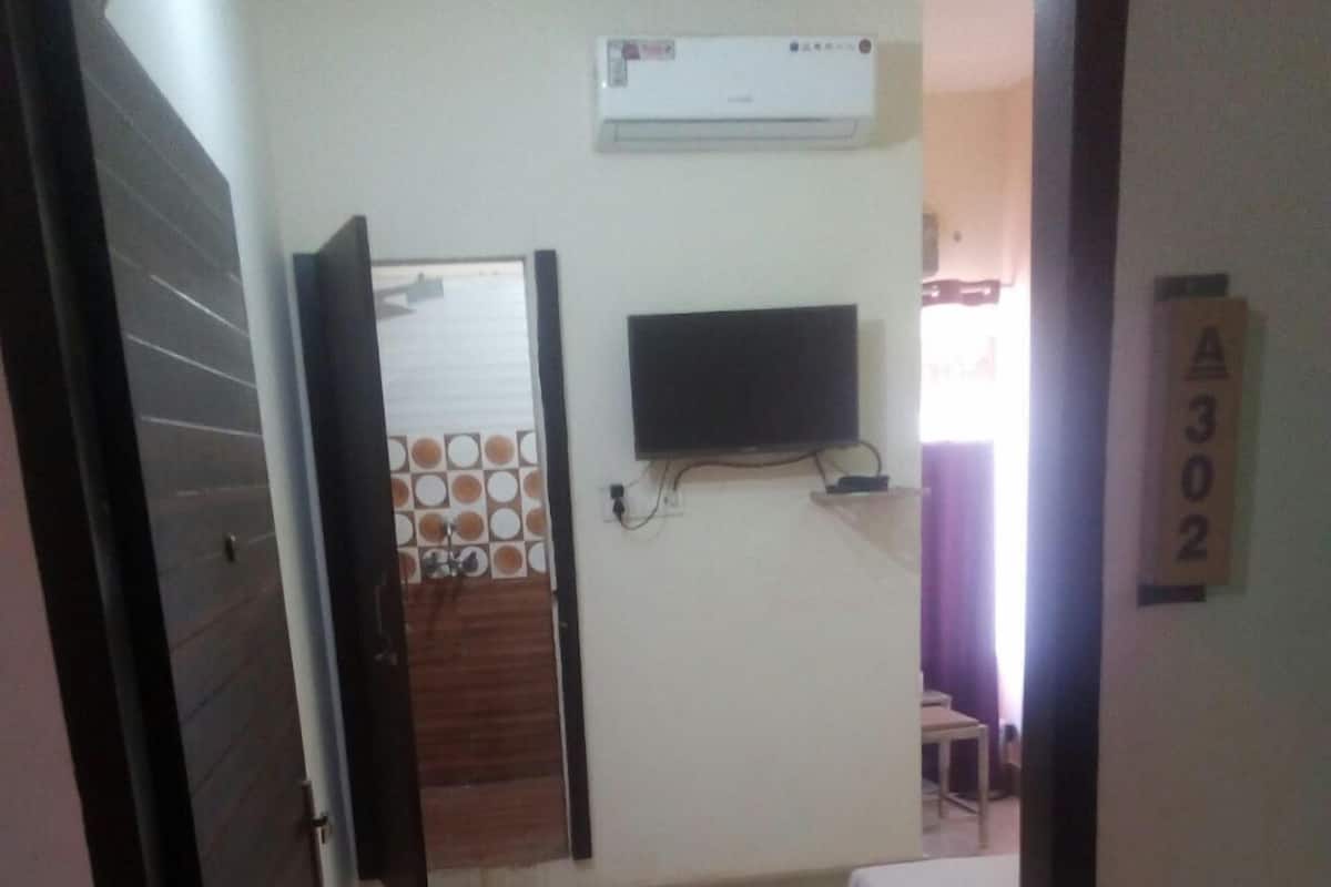 Un dormitorio con cama, televisor montado en la pared y aire acondicionado.