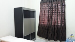 Ein Schlafzimmer mit einem Bett, einem Kleiderschrank, einem Vorhang und einem kleinen Tisch mit Flaschen.
