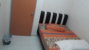 Ein kleines Zimmer mit einem Einzelbett, einem gestreiften Kopfteil, einer gemusterten Bettdecke und einer weißen Decke.