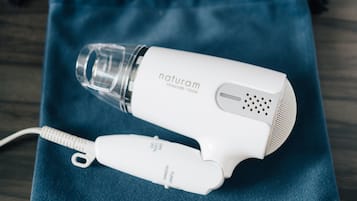 A white hair dryer with a transparent water bottle on a blue fabric surface.