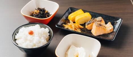 A table with four bowls containing rice, seaweed, fish, and a small dish of tofu.