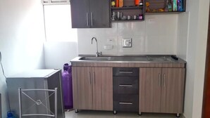A compact kitchen with a built-in sink, wooden cabinets, and a small countertop. - Come to Rionegro, Come to Life (Rionegro)