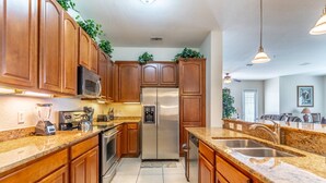 A modern kitchen with wooden cabinets, stainless steel appliances, granite countertops, and a built-in microwave. - New Listing! Vista Cay Resort, 7mi to Disney & 3mi to Universal - IT735 (Orlando)