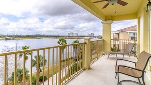 A balcony with a view of a lake, a ceiling fan, and two chairs. - New Listing! Vista Cay Resort, 7mi to Disney & 3mi to Universal - IT735 (Orlando)