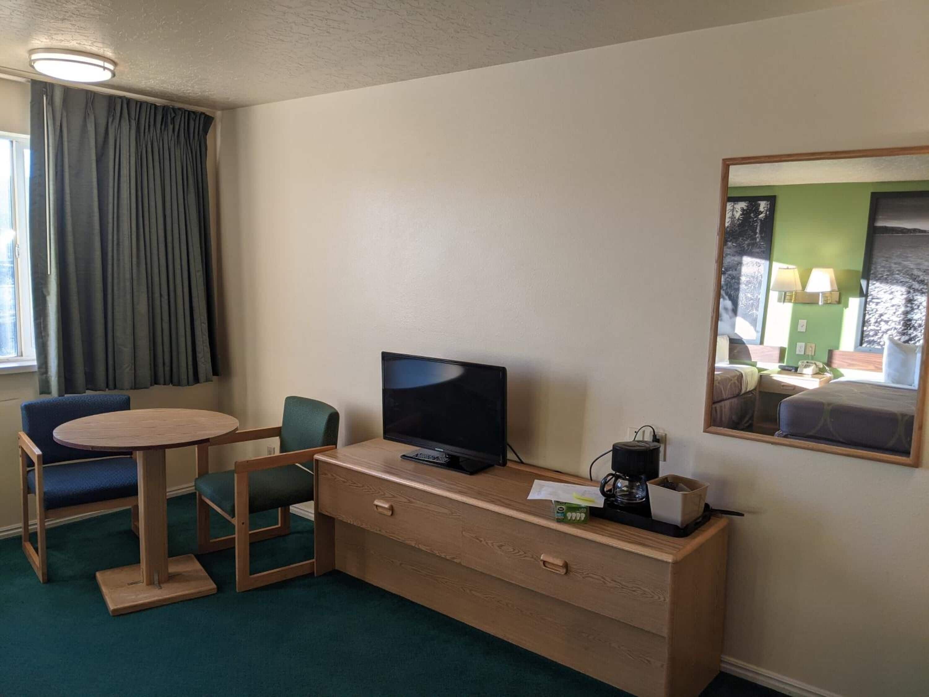 A hotel room with a desk, chair, television, and a bed.