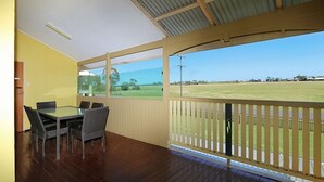 A covered outdoor area with a dining table and chairs, a view of a golf course, and a wooden deck. - Billys Beach House, Elliott heads (ELLIOTT HEADS)