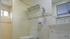 Casa de banho com sanita, secador de mãos e dispensador de sabonete.