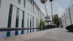 A modern building with a pool, palm trees, and a bar area. - Stay Inn Hotels (Reynosa)