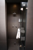 Un baño moderno con cabina de ducha de vidrio, inodoro y perchero para toallas.