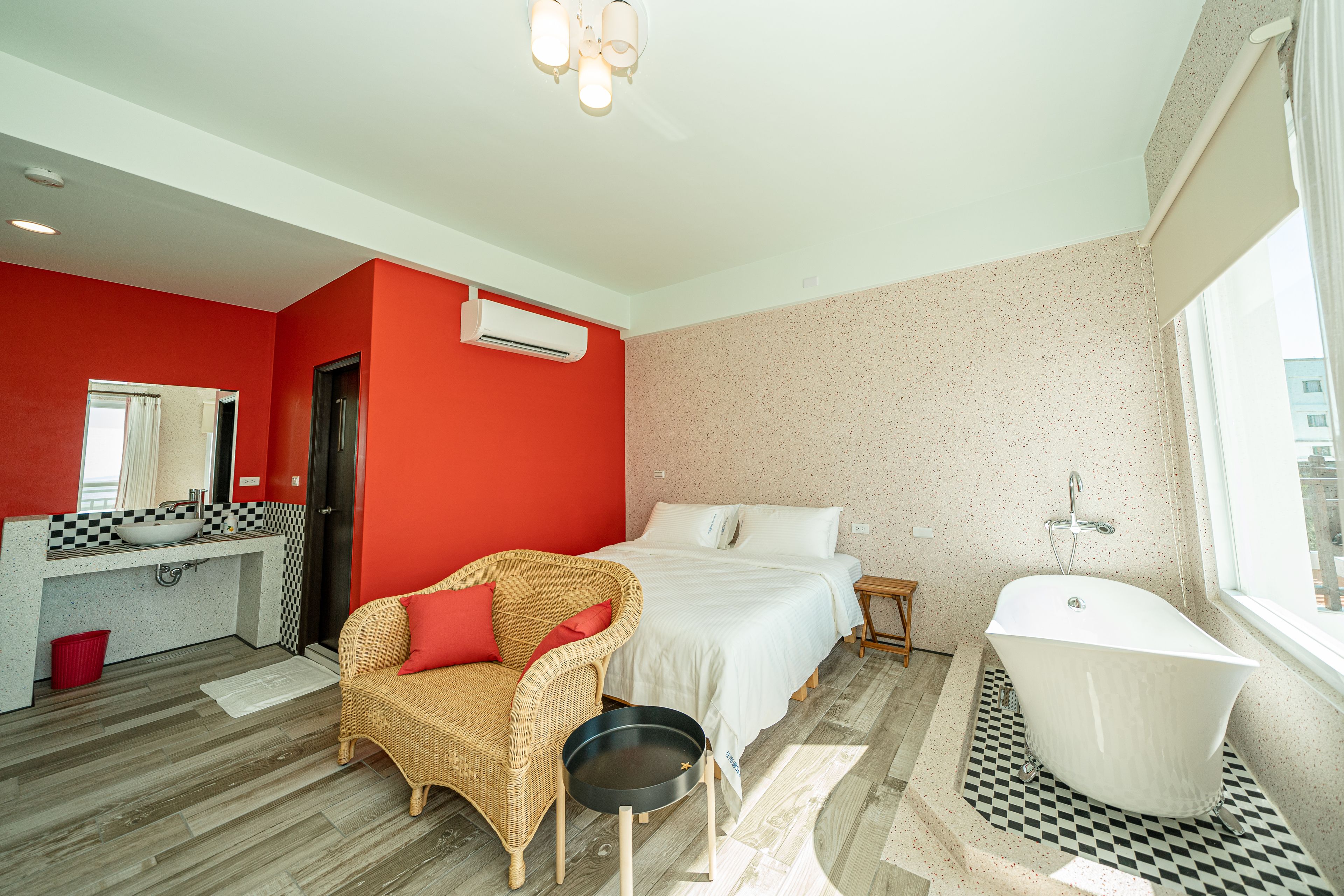A modern bathroom with a freestanding bathtub, a large mirror, and a red accent wall.
