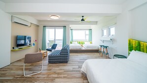 A hotel room with a bed, a sofa, a TV, and a balcony with a view.