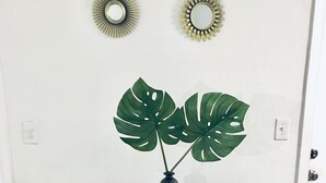 Une pièce avec une table ronde, deux chaises bleues, une plante en pot et deux miroirs muraux.