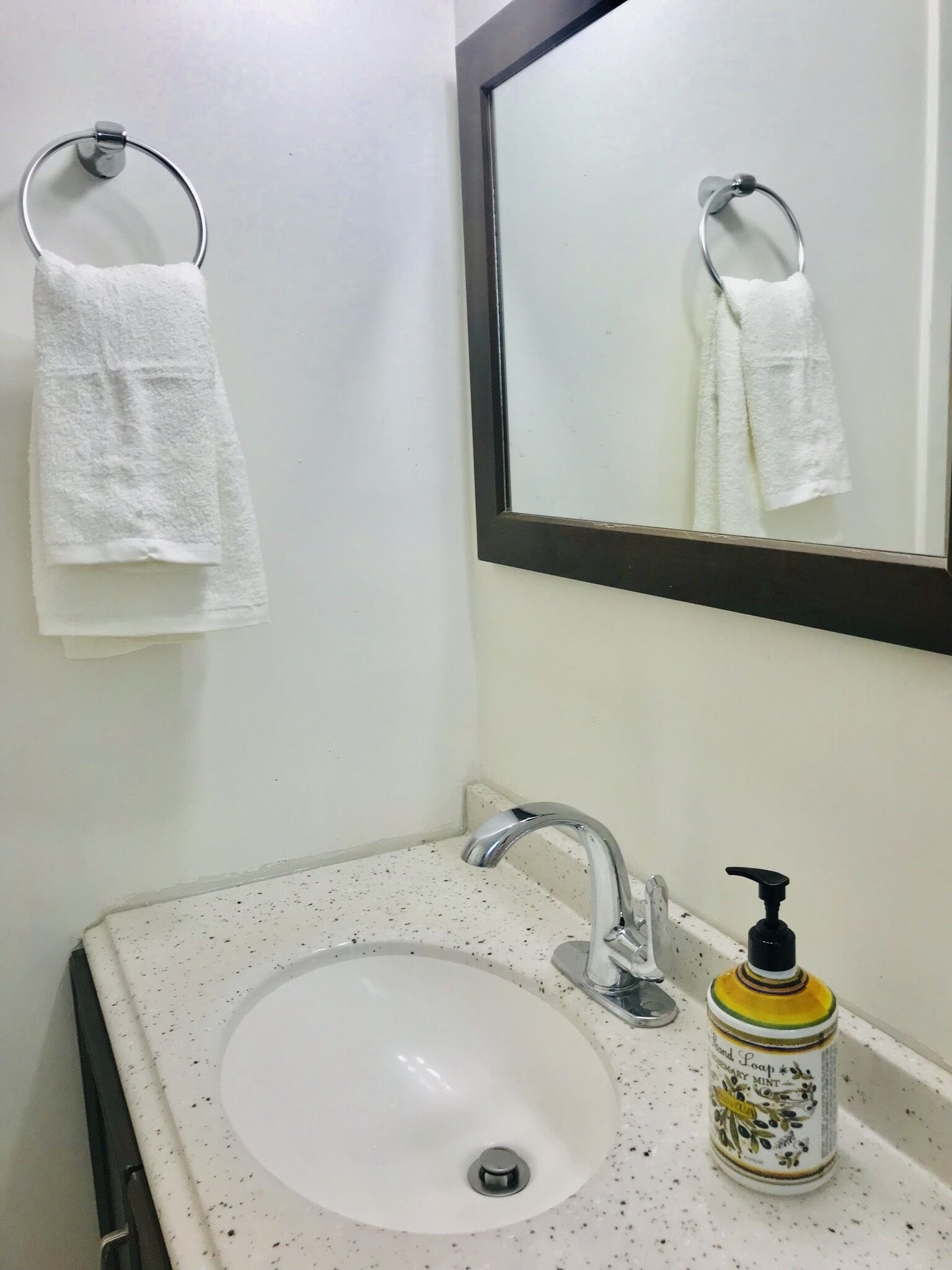 Un bagno con un lavandino bianco, uno specchio e un dispenser per sapone.