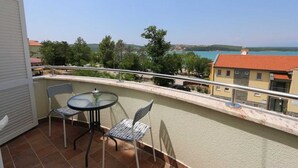 Un balcone con tavolo e due sedie, affacciato su un tratto d'acqua e edifici.