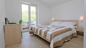 Una camera da letto con un letto, una scrivania, una sedia, un computer portatile e vista sull'esterno.