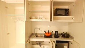 Una cocina compacta con microondas, pileta y heladera pequeña.