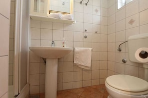 Casa de banho com lavatório, sanita e porta-toalhas.