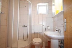 A bathroom with a shower, toilet, and sink.