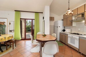 Cocina compacta con comedor, refrigerador, microondas y estufa a gas.