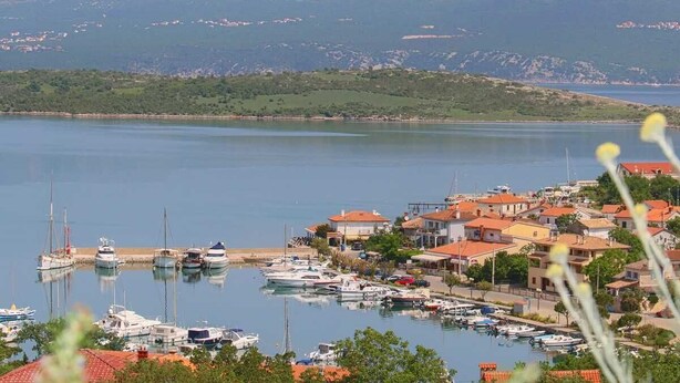 A marina with boats, a coastal town with houses, and mountains in the background. - Apartment Klimno View Point (Klimno - island Krk)