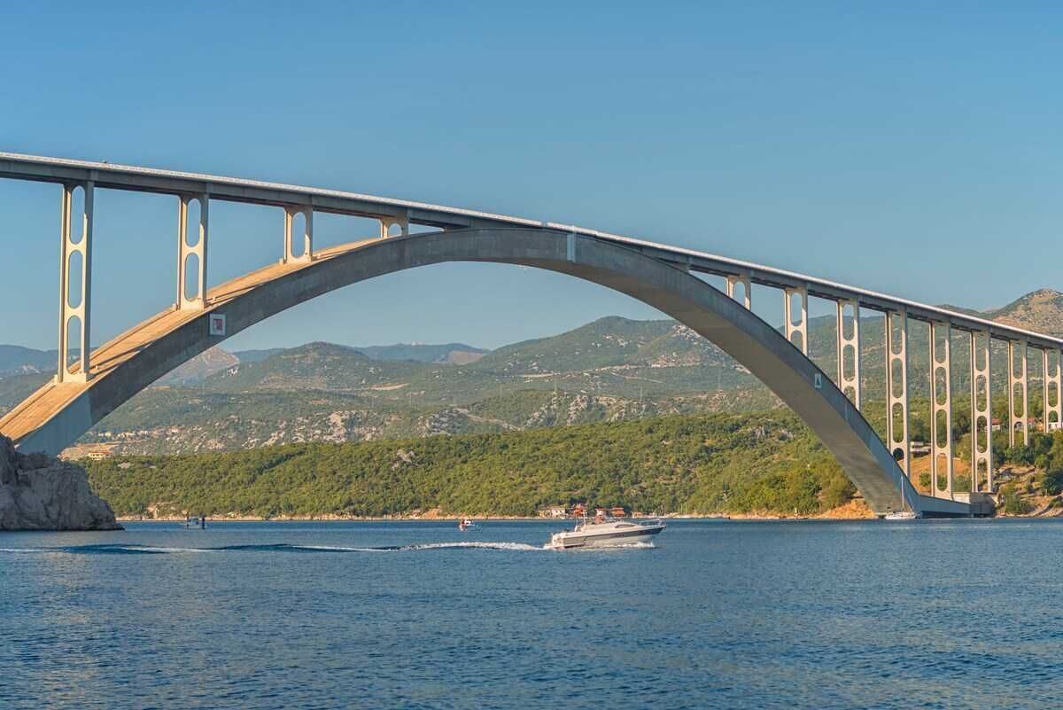 A large arched bridge over a body of water with a boat in the foreground.
