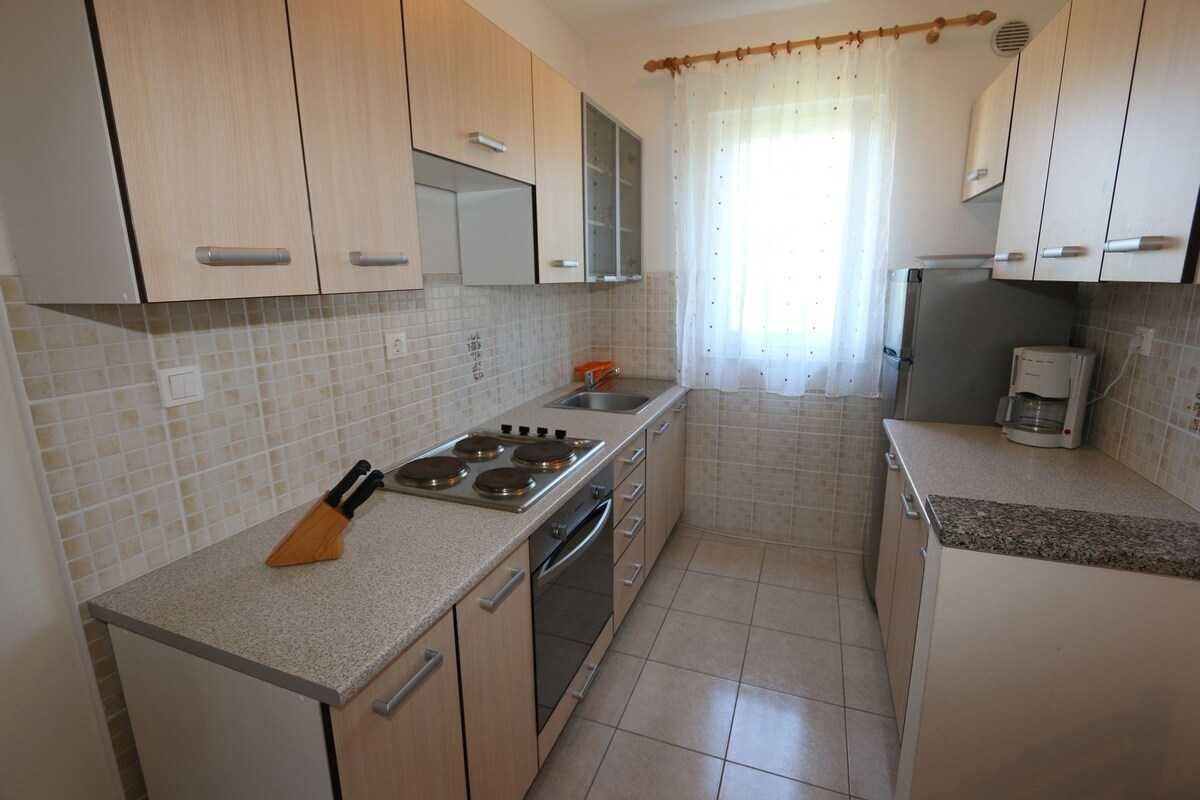 A kitchen with light wooden cabinets, a stainless steel stove, and a coffee maker.