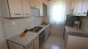 A kitchen with light wooden cabinets, a stainless steel stove, and a coffee maker.