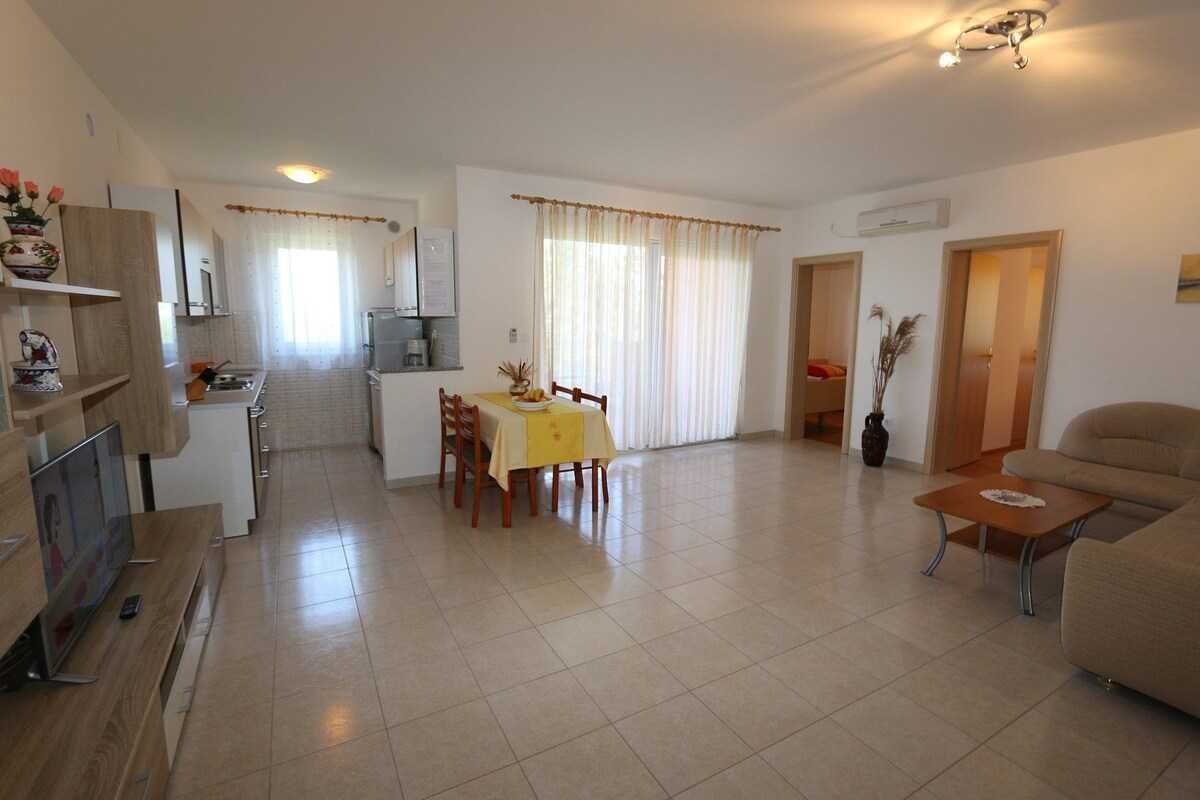 A spacious living area with a dining table, sofa, and kitchen in the background.